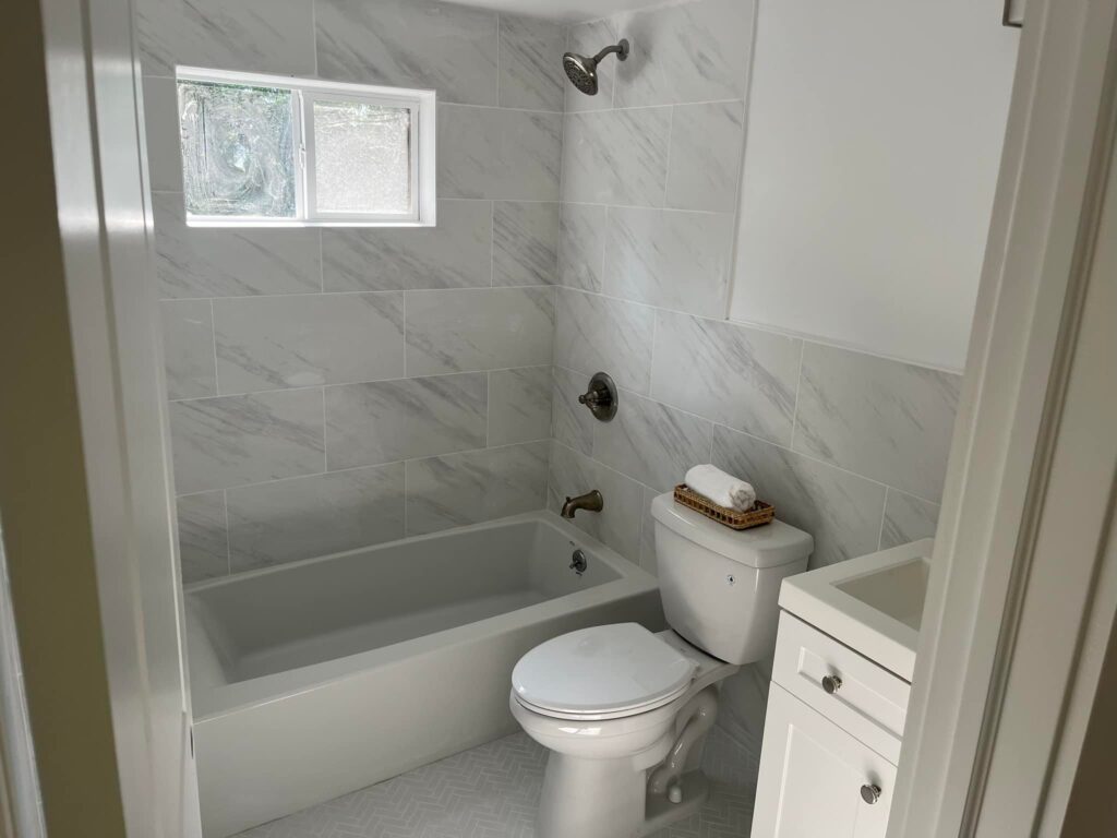 Plumber installing new bathroom tub spout fixture during remodel