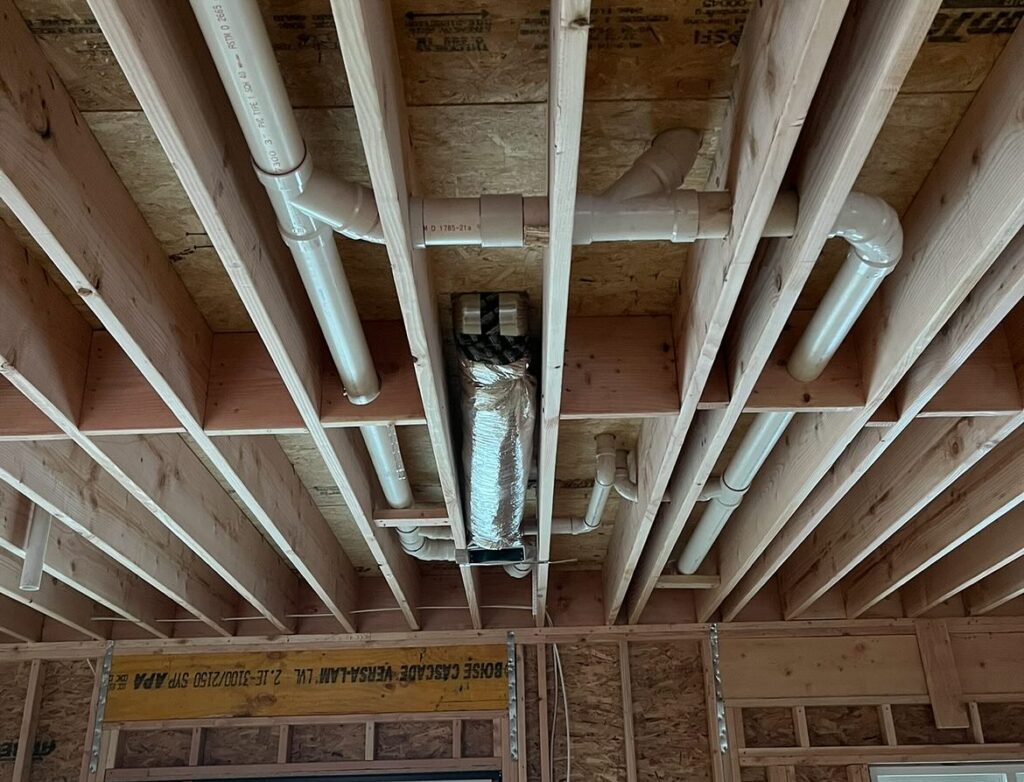 Plumber repairing leaking hot water pipe in basement ceiling