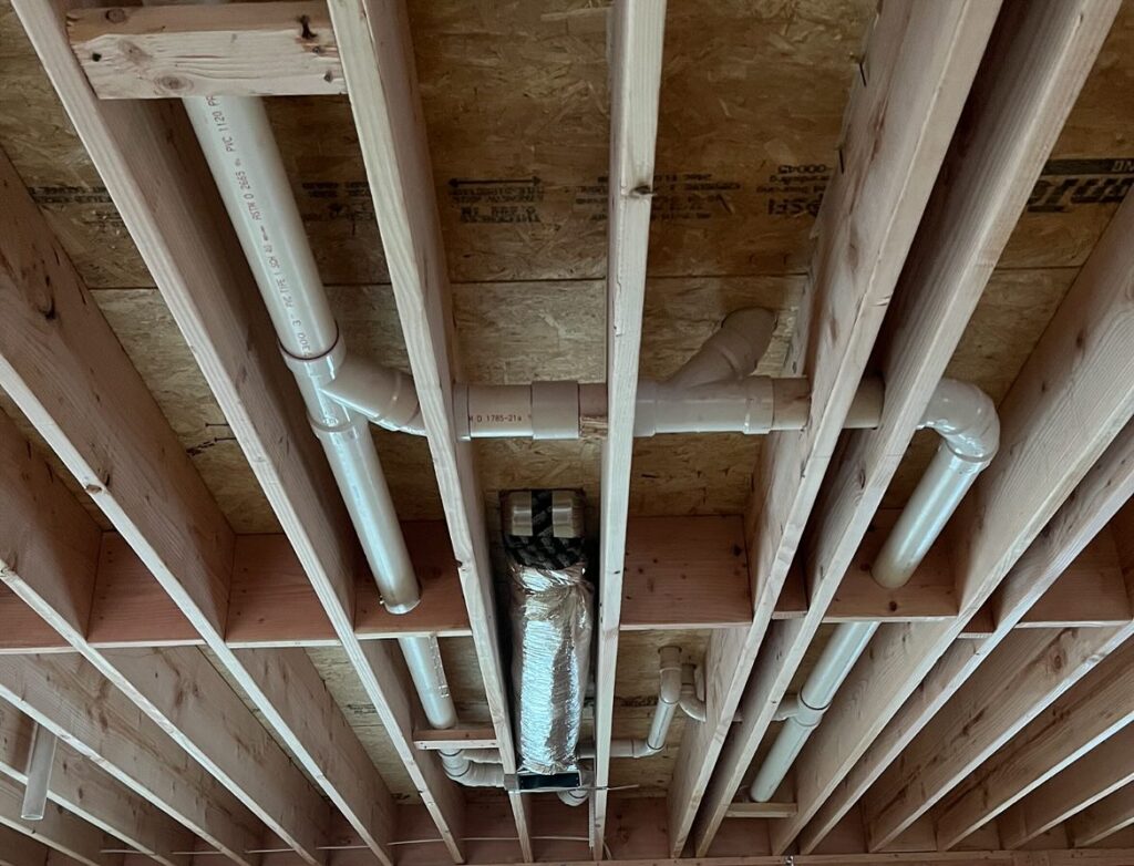Plumber repairing leaking hot water line beneath kitchen floor
