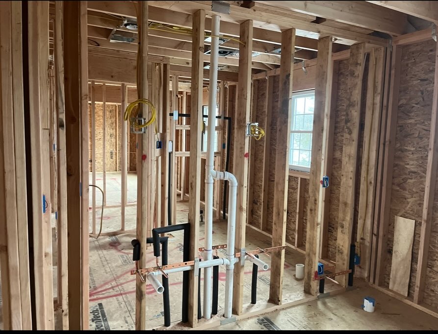 PVC plumbing drain lines installed inside residential bathroom wall framing