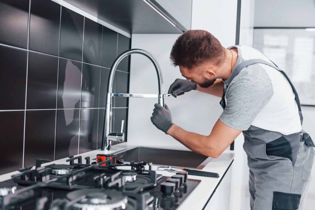 Plumber installing new dishwasher water supply line