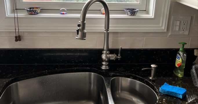 Plumber installing new kitchen sink plumbing during remodel