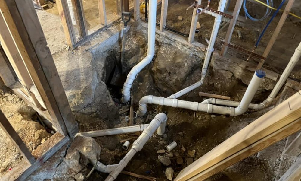 Plumber replacing damaged section of PVC drain line in basement