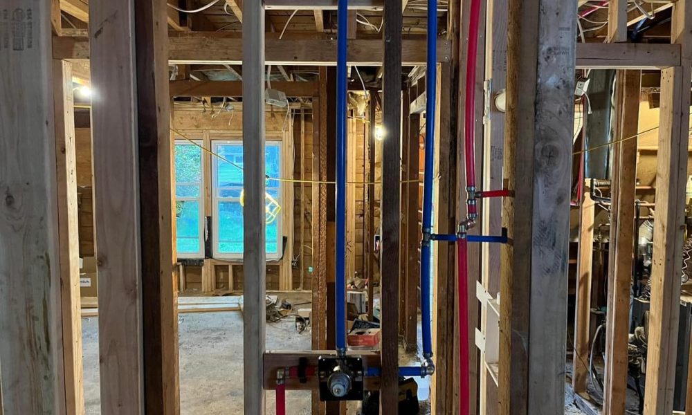 Plumber repairing leaking bathroom shower supply line inside wall