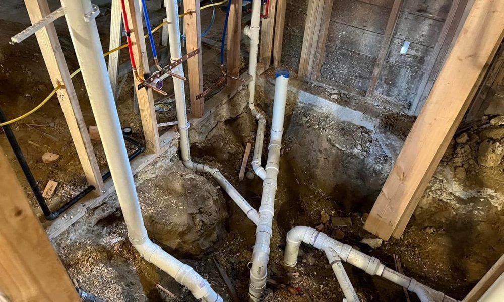 Plumber repairing leaking shower drain beneath bathroom floor