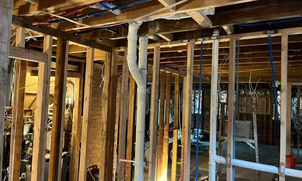 Plumber repairing leaking pipe joint in basement plumbing system