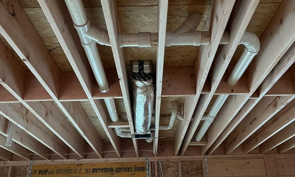 Plumber repairing leaking hot water pipe in basement ceiling