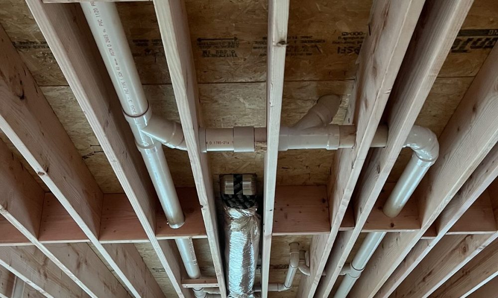 Plumber repairing leaking hot water line beneath kitchen floor